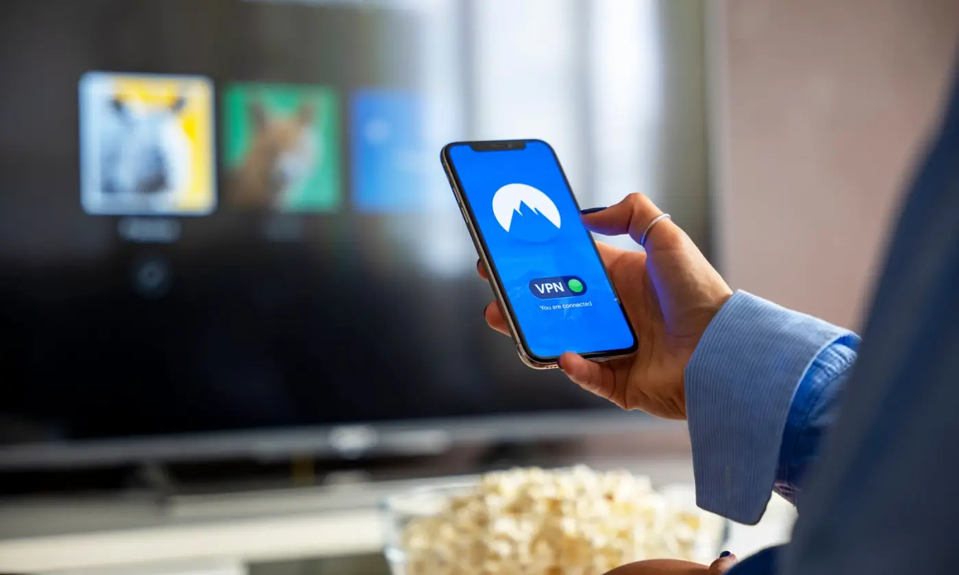 Una persona usa una VPN en el celular mientras ve la televisión